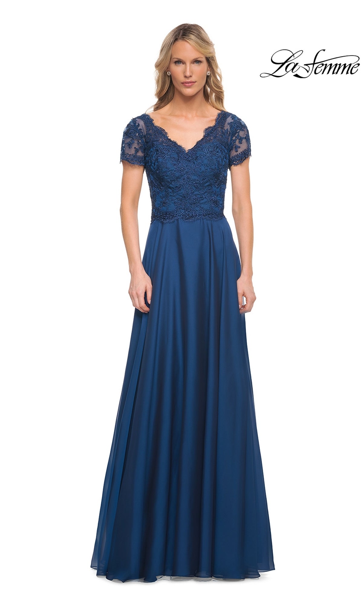 Woman in a floor-length midnight blue Long Formal Dress: La Femme 27098 with lace bodice and chiffon A-line skirt, standing against a white background. “La Femme” logo top right.